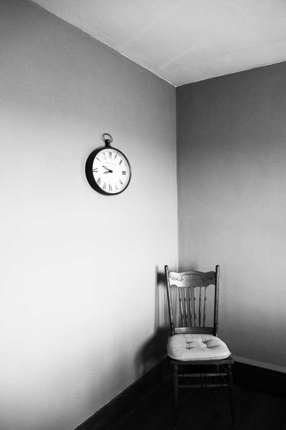 Clock and chair in an otherwise empty room. Time is 8:48 am.