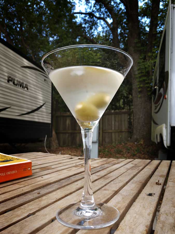 Photograph of a filled Martini glass sitting on a camp table in an RV park.