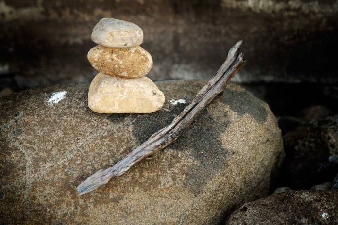 Photograph of a cairn with a dried, weathred wooden stick.